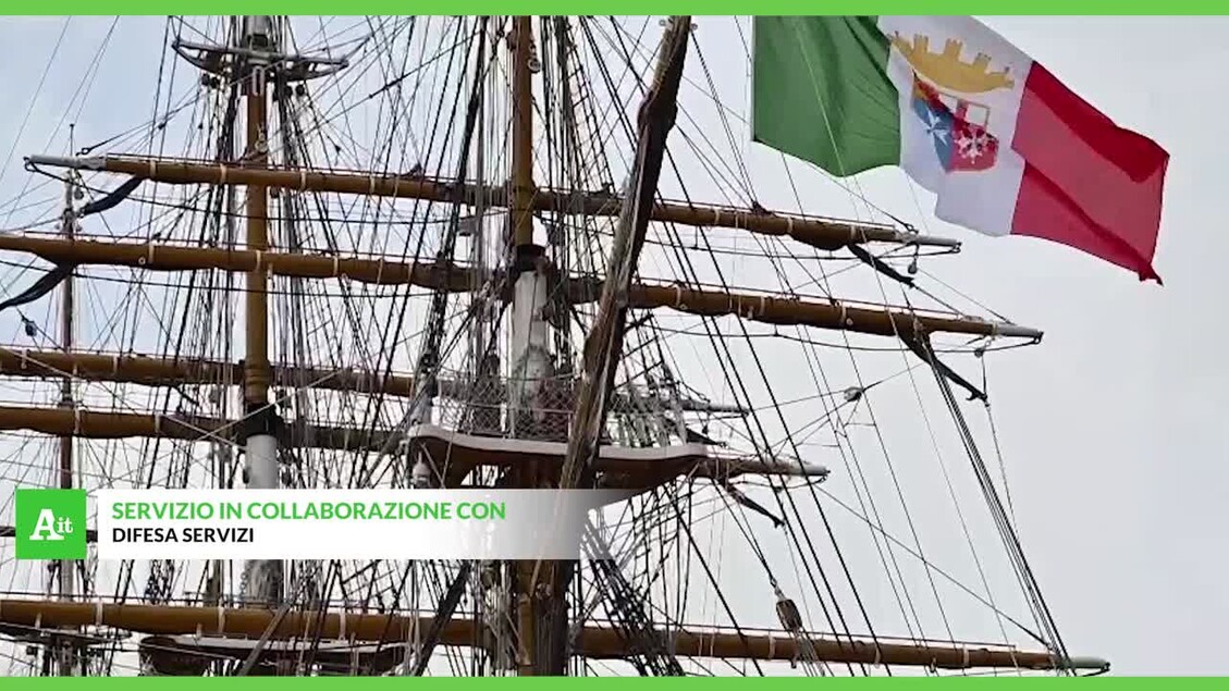 L'immagine mostra un primo piano di una nave a Trieste, con il Comandante Vespucci che offre un caloroso abbraccio. Sono visibili anche un ponte e una bandiera. La nave &egrave; un veliero, classificabile come nave ammiraglia, e rappresenta un'imbarcazione a vela.