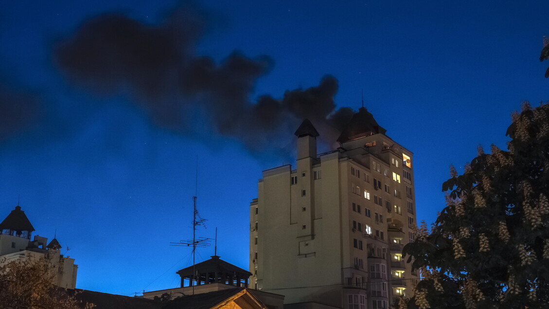 A Kiev, i droni russi riprendono gli attacchi mentre termina un cessate il fuoco di tre giorni. Si osserva un edificio con fumi neri che fuoriescono, segno di un attacco in corso. Il cielo &egrave; coperto di fumi e nuvole, contribuendo a un'atmosfera di conflitto. La scena &egrave; caratterizzata dalla presenza di una torre e da un contesto di guerra all'aperto.