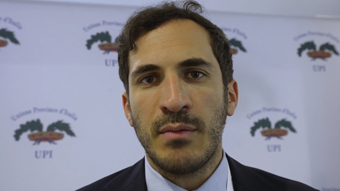 Enzo Lattuca &egrave; eletto presidente all'unanimit&agrave;. Nell'immagine &egrave; presente un uomo in abito elegante. Si notano anche dettagli come il volto e la barba dell'uomo. La scena potrebbe includere un contesto di riunione o evento formale, con altre persone visibili.