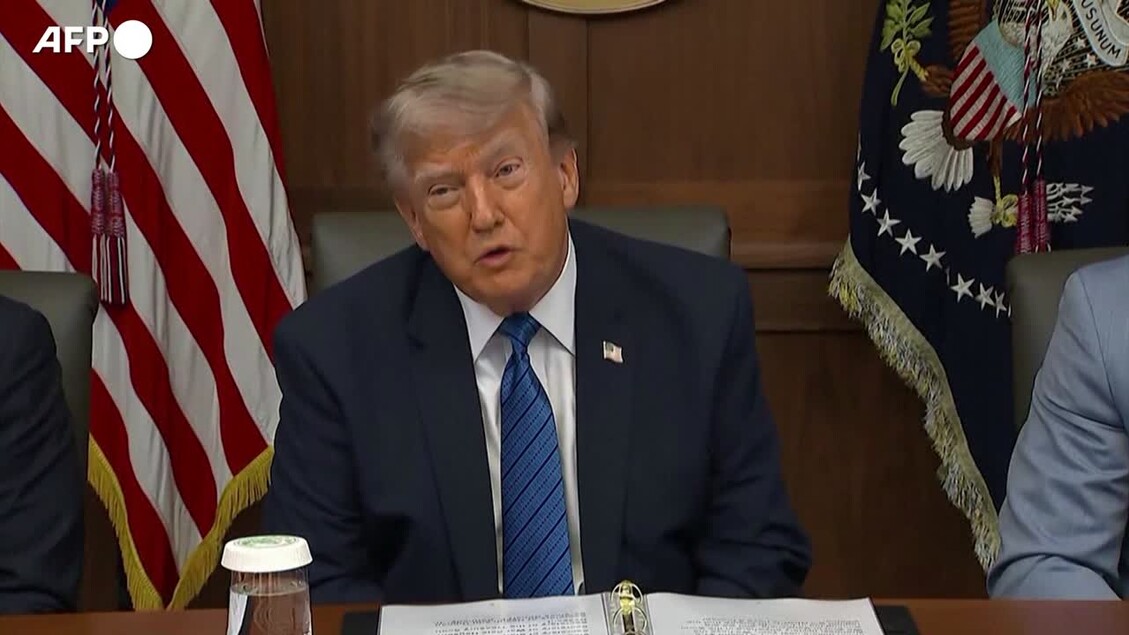 Donald Trump &egrave; riconoscibile nell'immagine. Si trova seduto a una scrivania, indossando un abito formale con una cravatta. Il contesto riguarda il disarmo di Hamas, con Trump che afferma: &ldquo;Israele &egrave; molto contento a riguardo&rdquo;. L'immagine presenta un ambiente interno con altre persone visibili.
