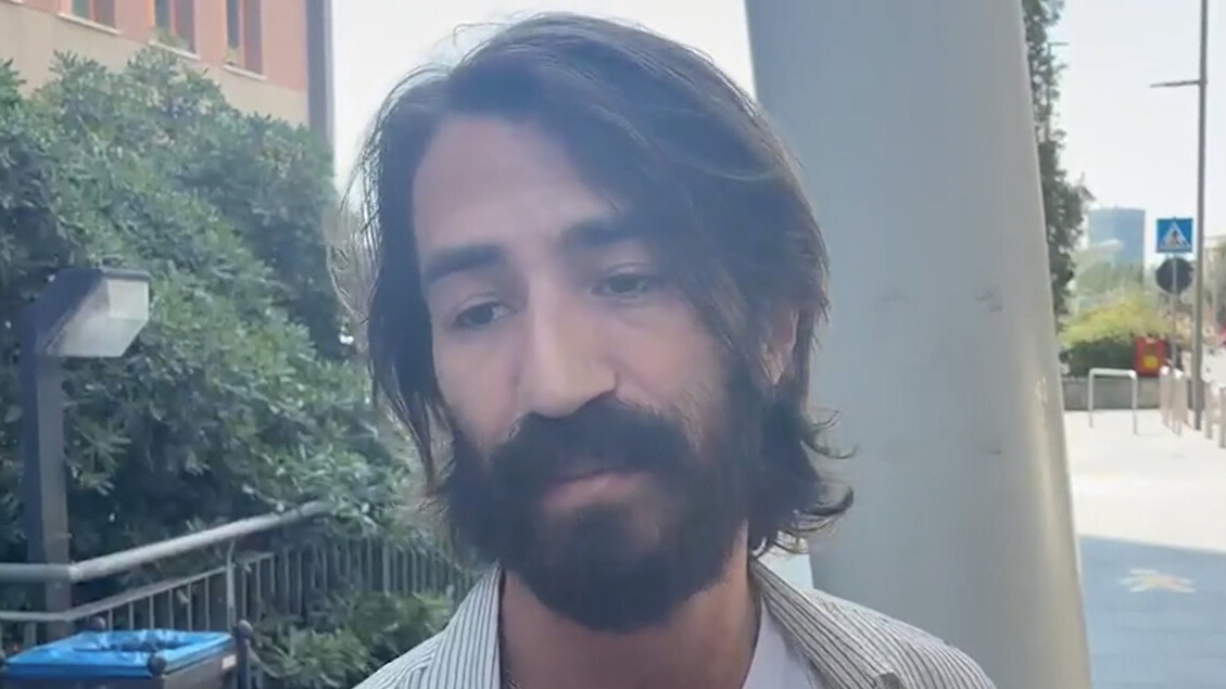 L'immagine mostra un uomo con capelli lunghi e barba, che si trova a Milano, al San Raffaele, in compagnia della sua ex compagna e della figlia. Sono visibili i volti delle persone, evidenziando la presenza di un adulto maschio.