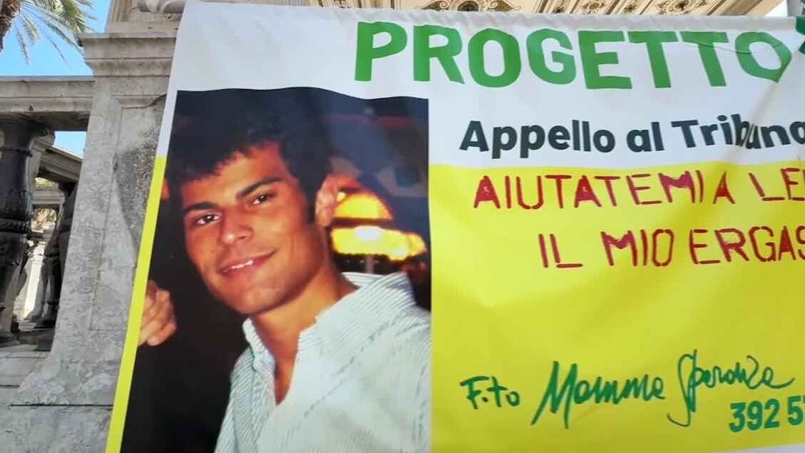 L'immagine presenta un poster di un uomo, accompagnato da un messaggio della madre di Caso Maiorana che afferma: Nessun caso di scomparsa va archiviato. Il contesto suggerisce un appello per la sensibilizzazione su casi di scomparsa. Sono visibili elementi come un banner e scritte che supportano il tema dell'immagine. Una persona &egrave; presente, ma non ci sono ulteriori dettagli specifici su di essa.