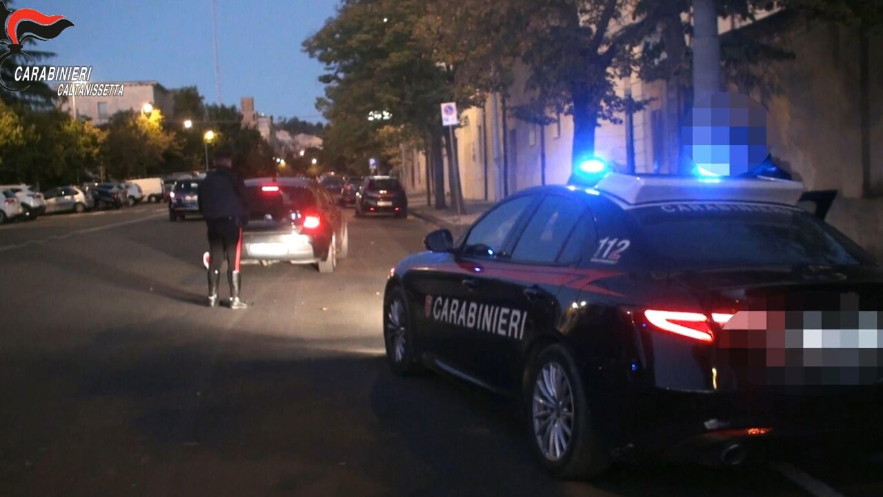 L'immagine rappresenta un'operazione della polizia nel Nisseno, con nove arresti legati alla mafia. &Egrave; visibile un'auto della polizia con le luci accese. Il contesto &egrave; caratterizzato da elementi di trasporto e veicoli, suggerendo un'azione di sicurezza pubblica. Sono presenti anche riferimenti ai Carabinieri e al numero di emergenza 112, che indicano l'importanza dell'intervento delle forze dell'ordine.