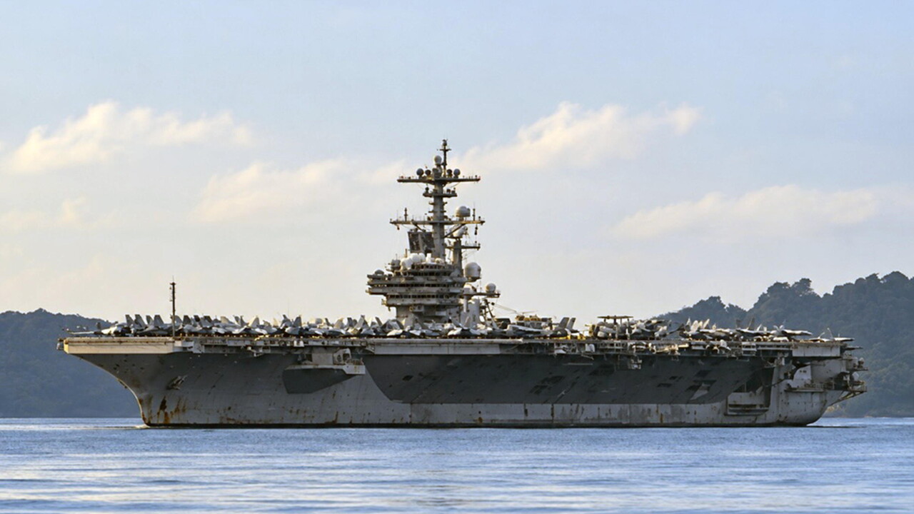 La portaerei statunitense USS George H.W. Bush arriva a Phuket dopo un incarico in Medio Oriente. Si tratta di una grande nave militare visibile nell'acqua, classificata come veicolo navale. L'immagine rappresenta un contesto di trasporto militare all'aperto, con il cielo e l'acqua circostante.