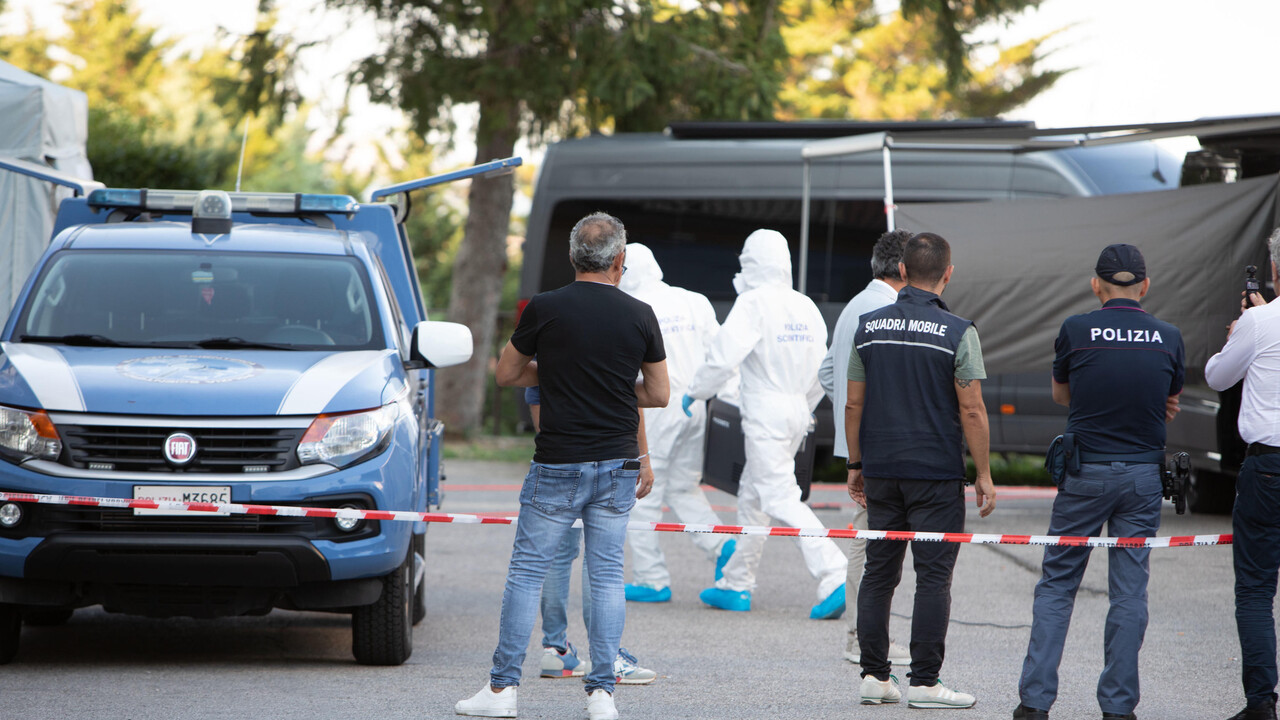 Un gruppo di persone in tute protettive &egrave; presente a Pietracatella, dove si &egrave; verificato un evento legato a una morte avvelenata. &Egrave; visibile anche un'auto blu con del nastro bianco e rosso. La scena &egrave; identificata come un luogo di crimine.