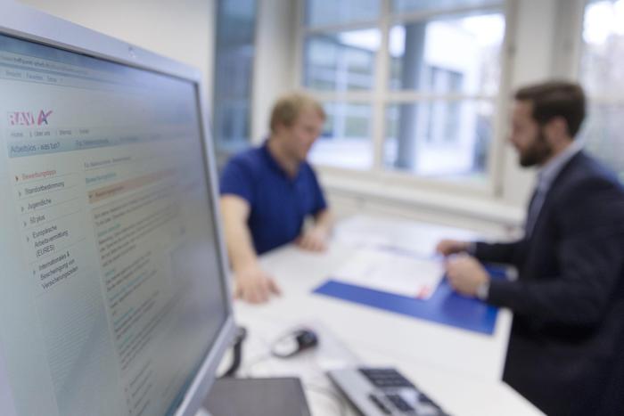 Un uomo guarda un monitor di un computer all'interno di un ambiente chiuso. L'immagine &egrave; collegata all'implementazione di un'iniziativa di immigrazione di massa. L'uomo &egrave; un adulto e indossa abbigliamento da lavoro.
