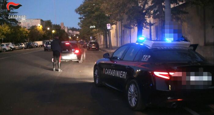 L'immagine rappresenta un'operazione della polizia nel Nisseno, con nove arresti legati alla mafia. &Egrave; visibile un'auto della polizia con le luci accese. Il contesto &egrave; caratterizzato da elementi di trasporto e veicoli, suggerendo un'azione di sicurezza pubblica. Sono presenti anche riferimenti ai Carabinieri e al numero di emergenza 112, che indicano l'importanza dell'intervento delle forze dell'ordine.
