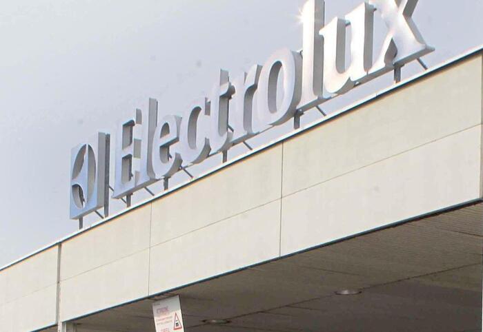 L'immagine mostra uno stabilimento Electrolux a Cerreto, con un rinnovo di 12 mesi per un contratto di solidariet&agrave;. &Egrave; presente un cartello, che potrebbe contenere informazioni relative all'azienda. Sullo sfondo si intravede un cielo e un edificio, che contribuiscono al contesto industriale della scena.