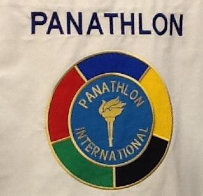 L'immagine rappresenta un evento che celebra un'intesa tra Coni, Cip e Panathlon Area 12 per promuovere i valori dello sport. &Egrave; presente un logo circolare su una maglietta bianca, che appare anche su una superficie bianca. Piercarlo Lunardi &egrave; confermato presidente del Panathlon Vda. Il logo e l'emblema del Panathlon sono visibili, sottolineando l'importanza dell'evento.