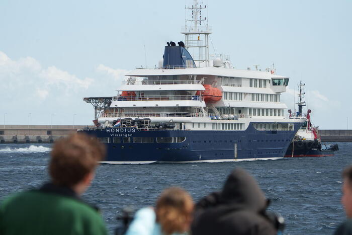 La nave da crociera Mv Hondius &egrave; visibile in acqua. I passeggeri finali della Mv Hondius attendono lo sbarco dopo un focolaio di hantavirus. La scena rappresenta un'imbarcazione di grandi dimensioni, associata al trasporto e all'architettura navale.