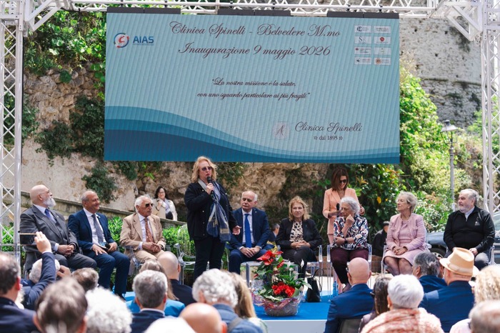 La storica "Clinica Spinelli" ha una nuova vita grazie a un progetto dell'Aias di Cetraro. Un uomo parla in un microfono di fronte a una grande folla di persone. Sul palco ci sono diversi individui, tra cui un uomo in giacca e cravatta. Alcuni partecipanti tengono certificati. L'evento si svolge in un ambiente interno, probabilmente un seminario o una conferenza.