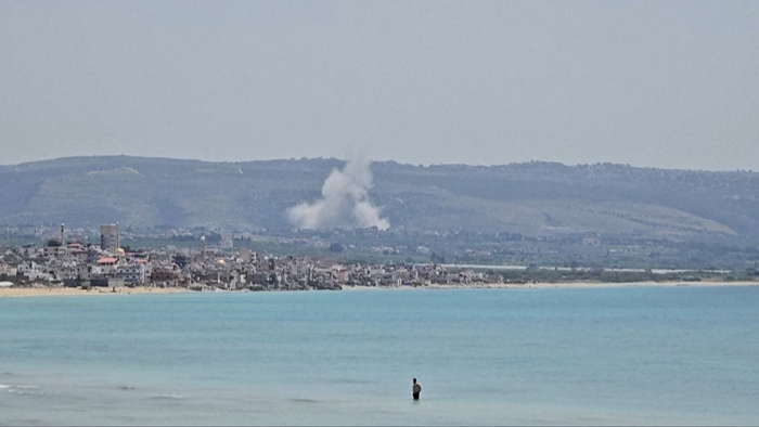L'immagine mostra una grande nave in acqua, identificata come una nave mercantile. Il contesto &egrave; legato a tensioni geopolitiche tra Stati Uniti, Iran e Israele, suggerendo un ambiente di conflitto. La scena &egrave; all'aperto e rappresenta un elemento di trasporto marittimo.