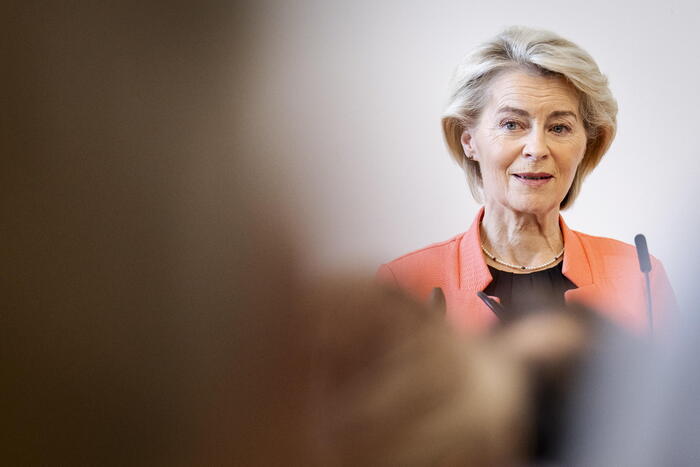 Ursula von der Leyen &egrave; riconoscibile nell'immagine, che rappresenta il Vertice Europeo sull'Intelligenza Artificiale e i Bambini a Copenaghen. Una donna indossa una giacca arancione. L'immagine mostra un adulto, in particolare una donna, con un sorriso. Il contesto &egrave; fotografico e presenta un volto umano.