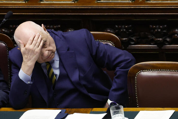 Un uomo in abito elegante tiene la testa tra le mani. La scena si riferisce a Nordio, che discute la necessit&agrave; di cambiare la legge in seguito all'ingiustizia di Garlasco. L'immagine mostra il volto dell'uomo, evidenziando l'espressione di preoccupazione o riflessione.