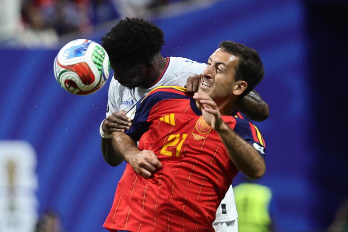 La scena rappresenta una partita di calcio della Coppa del Mondo FIFA 2026, tra Spagna e Capo Verde. Un uomo in uniforme rossa tiene un pallone da calcio in mano. Mikel Oyarzabal &egrave; riconoscibile nell'immagine. L'evento &egrave; un incontro sportivo di calcio.