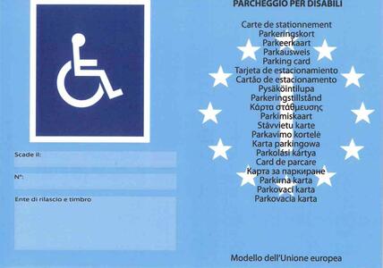 Un cartello blu e bianco presenta una stella bianca su uno sfondo blu. Sono visibili anche altre stelle bianche sul cartello. Il testo "PARCHEGGIO PER DISABILI" &egrave; presente, indicando la funzione del cartello. Inoltre, il contesto include elementi come pubblicit&agrave; e simboli, suggerendo un ambiente urbano.