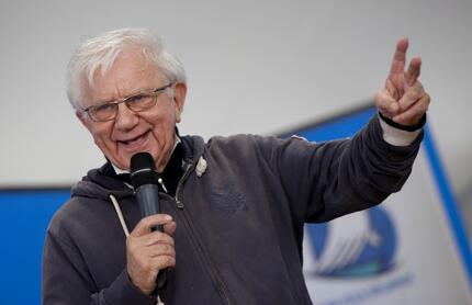 E' morto Don Mazzi, fondatore della comunit&agrave; Exodus. Un uomo tiene un microfono durante una conferenza stampa. La scena include un pubblico e diverse persone presenti.