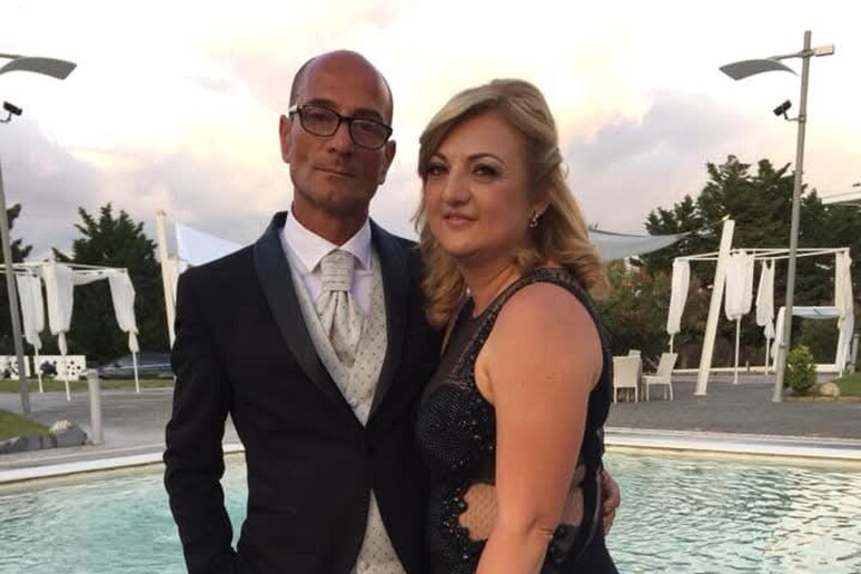 Un uomo e una donna indossano abiti formali. L'immagine &egrave; associata a un contesto di giustizia, poich&eacute; la moglie dell'operaio morto esprime il desiderio di ottenere giustizia. Gli abiti includono un completo e un vestito elegante.