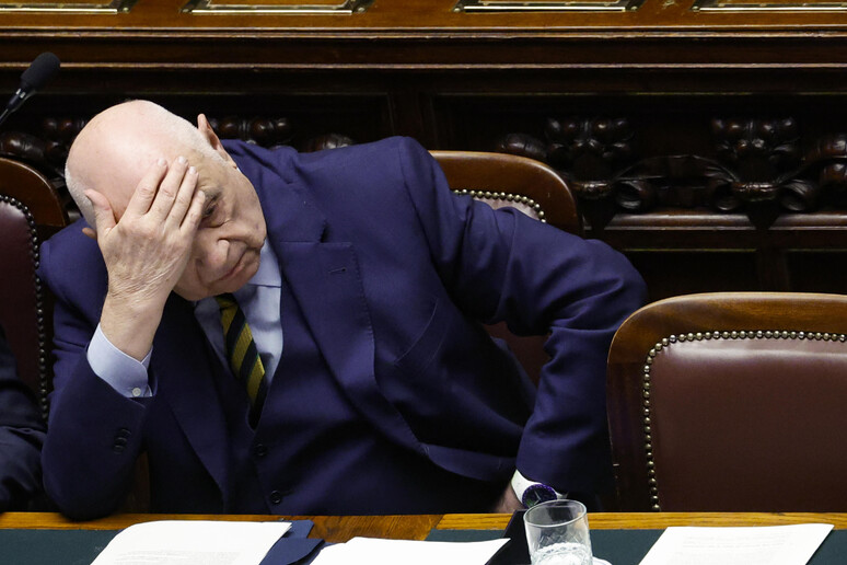 Un uomo in abito elegante tiene la testa tra le mani. La scena si riferisce a Nordio, che discute la necessit&agrave; di cambiare la legge in seguito all'ingiustizia di Garlasco. L'immagine mostra il volto dell'uomo, evidenziando l'espressione di preoccupazione o riflessione.