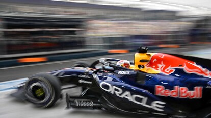 Max Verstappen &egrave; in pole position nella Sprint a Singapore, seguito da Charles Leclerc al terzo posto. La scena si svolge su un circuito di auto da corsa, caratterizzato da veicoli di Formula Uno. Sono presenti elementi tipici del motorsport, come pneumatici e ruote, che arricchiscono il contesto della gara.
