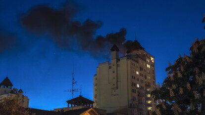 A Kiev, i droni russi riprendono gli attacchi mentre termina un cessate il fuoco di tre giorni. Si osserva un edificio con fumi neri che fuoriescono, segno di un attacco in corso. Il cielo &egrave; coperto di fumi e nuvole, contribuendo a un'atmosfera di conflitto. La scena &egrave; caratterizzata dalla presenza di una torre e da un contesto di guerra all'aperto.